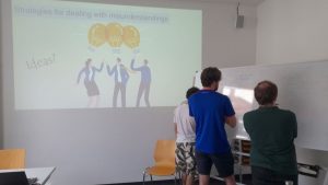 Studierende diskutieren vor einem Whiteboard